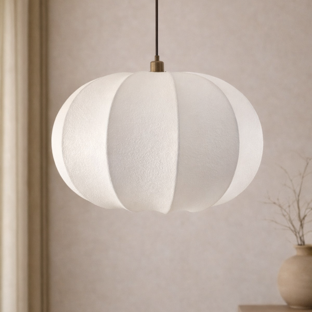 White pendant lamp hanging against a neutral wall with a vase on a shelf.