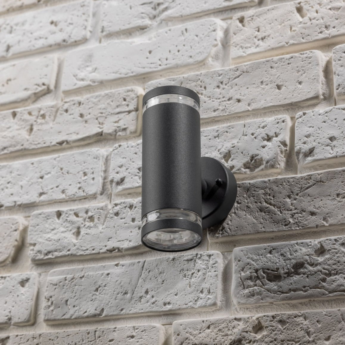 Our Jennifer dark grey outdoor wall mounted up and down cylinder outdoor light would look perfect in a modern or more traditional home design. Outside wall lights can provide atmospheric light in your garden, at the front door or on the terrace as well as a great security solution. It is designed for durability and longevity with its robust material producing a fully weatherproof and water resistant light fitting