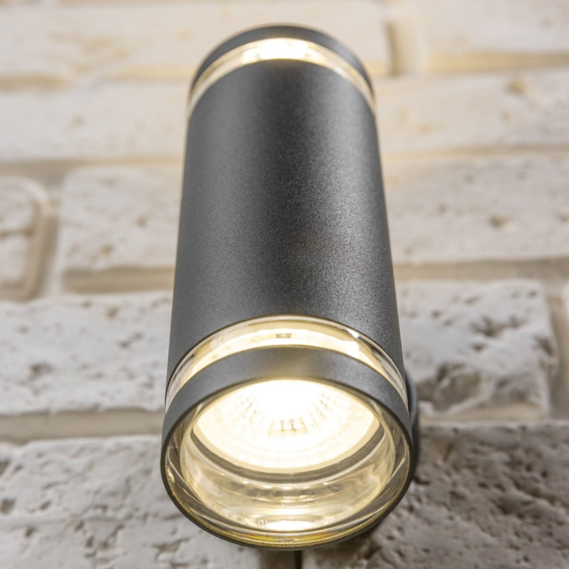 Our Jennifer dark grey outdoor wall mounted up and down cylinder outdoor light would look perfect in a modern or more traditional home design. Outside wall lights can provide atmospheric light in your garden, at the front door or on the terrace as well as a great security solution. It is designed for durability and longevity with its robust material producing a fully weatherproof and water resistant light fitting