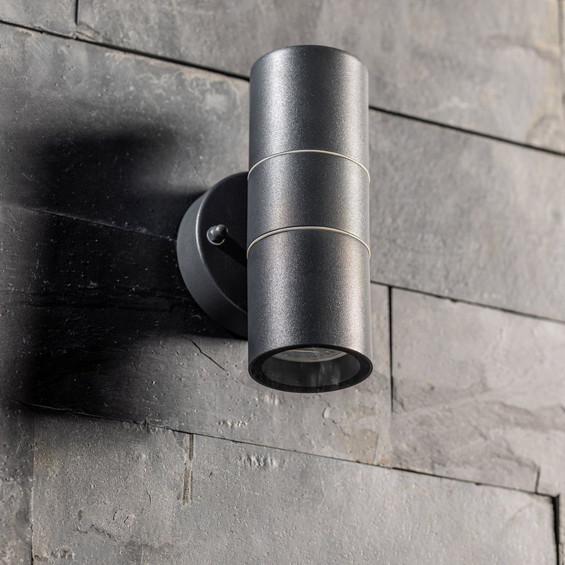 Our Mia outdoor up and down outdoor wall light is modern and stylish in its appearance.  It comes in a cylinder design mounted on a circular back plate and complete with clear glass diffusers. It is designed for durability and longevity with its robust material producing a fully weatherproof and water resistant light fitting