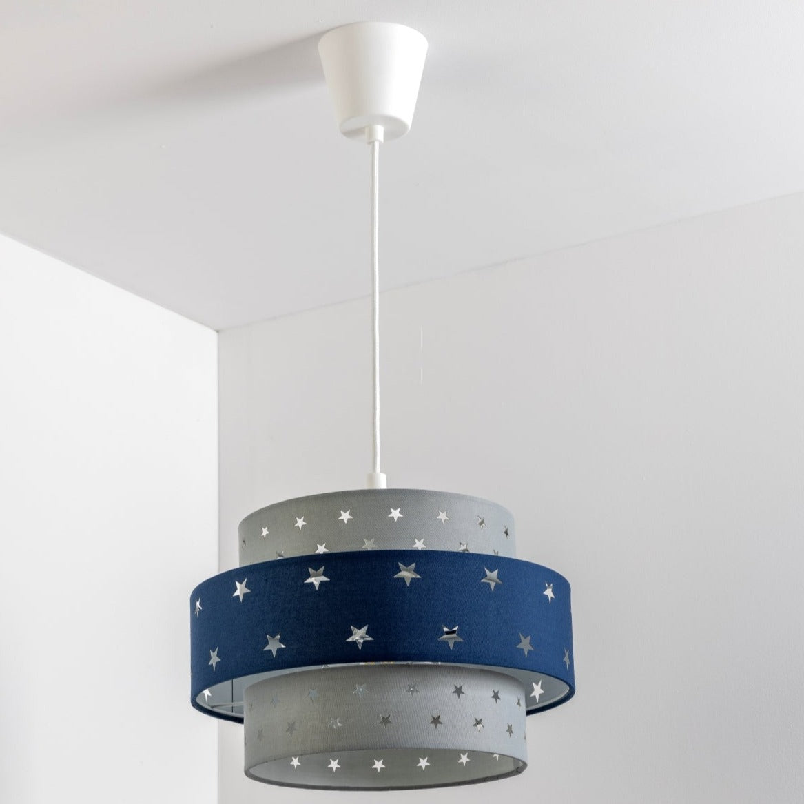 Our grey and navy two tiered star shade features a mixture of large and small sweet stars cut out across a grey and navy background. When your lamp is turned on it will shine out through these cut-outs, mimicking a beautiful night sky. This lampshade is made with soft-touch fabric for a little bit of luxury.