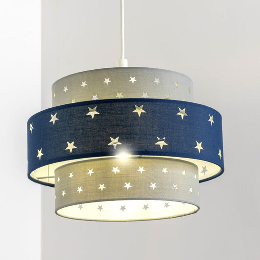 Our grey and navy two tiered star shade features a mixture of large and small sweet stars cut out across a grey and navy background. When your lamp is turned on it will shine out through these cut-outs, mimicking a beautiful night sky. This lampshade is made with soft-touch fabric for a little bit of luxury.