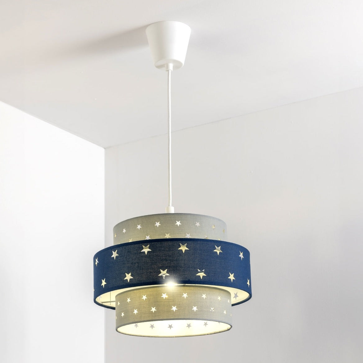 Our grey and navy two tiered star shade features a mixture of large and small sweet stars cut out across a grey and navy background. When your lamp is turned on it will shine out through these cut-outs, mimicking a beautiful night sky. This lampshade is made with soft-touch fabric for a little bit of luxury.