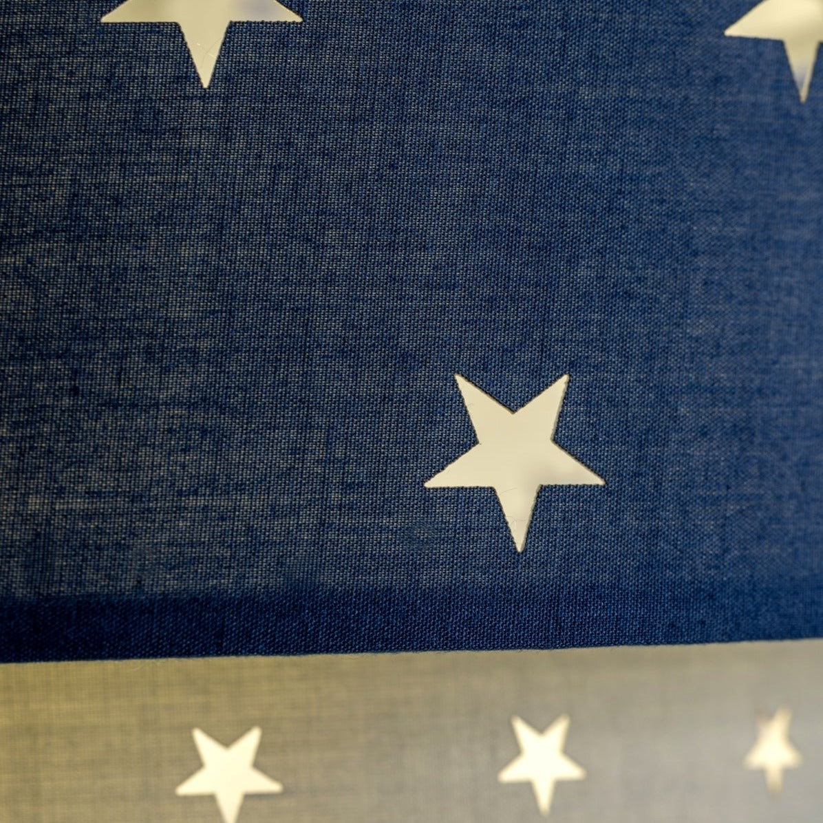 Our grey and navy two tiered star shade features a mixture of large and small sweet stars cut out across a grey and navy background. When your lamp is turned on it will shine out through these cut-outs, mimicking a beautiful night sky. This lampshade is made with soft-touch fabric for a little bit of luxury.