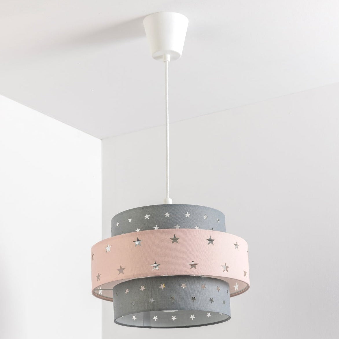 Our grey and pink two tiered star shade features a mixture of large and small sweet stars cut out across a grey and pink background. When your lamp is turned on it will shine out through these cut-outs, mimicking a beautiful night sky. This lampshade is made with soft-touch fabric for a little bit of luxury.