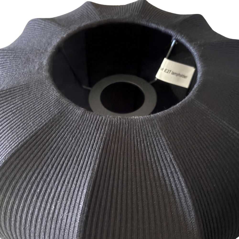 Close-up of a textured black vase with a brand label on a white background
