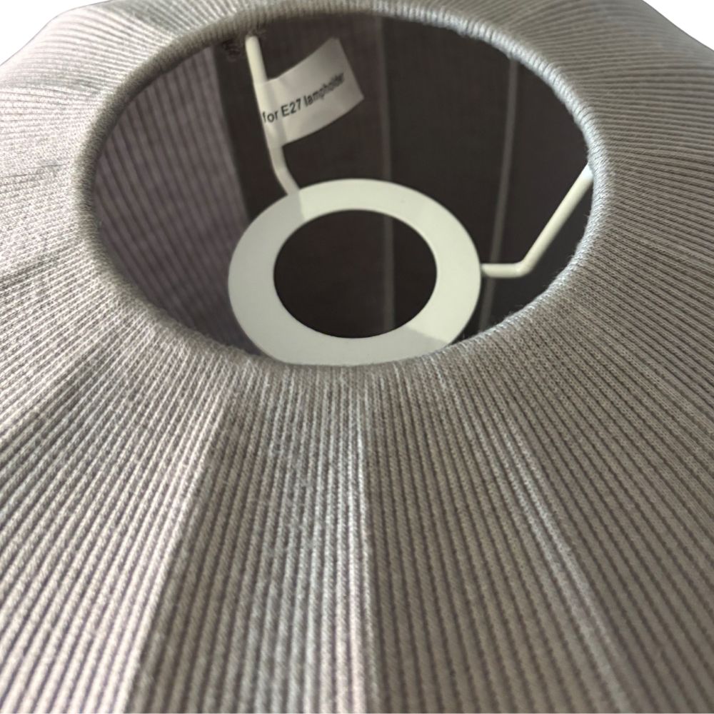 Close-up of a textured gray light fixture with a white ring and label.