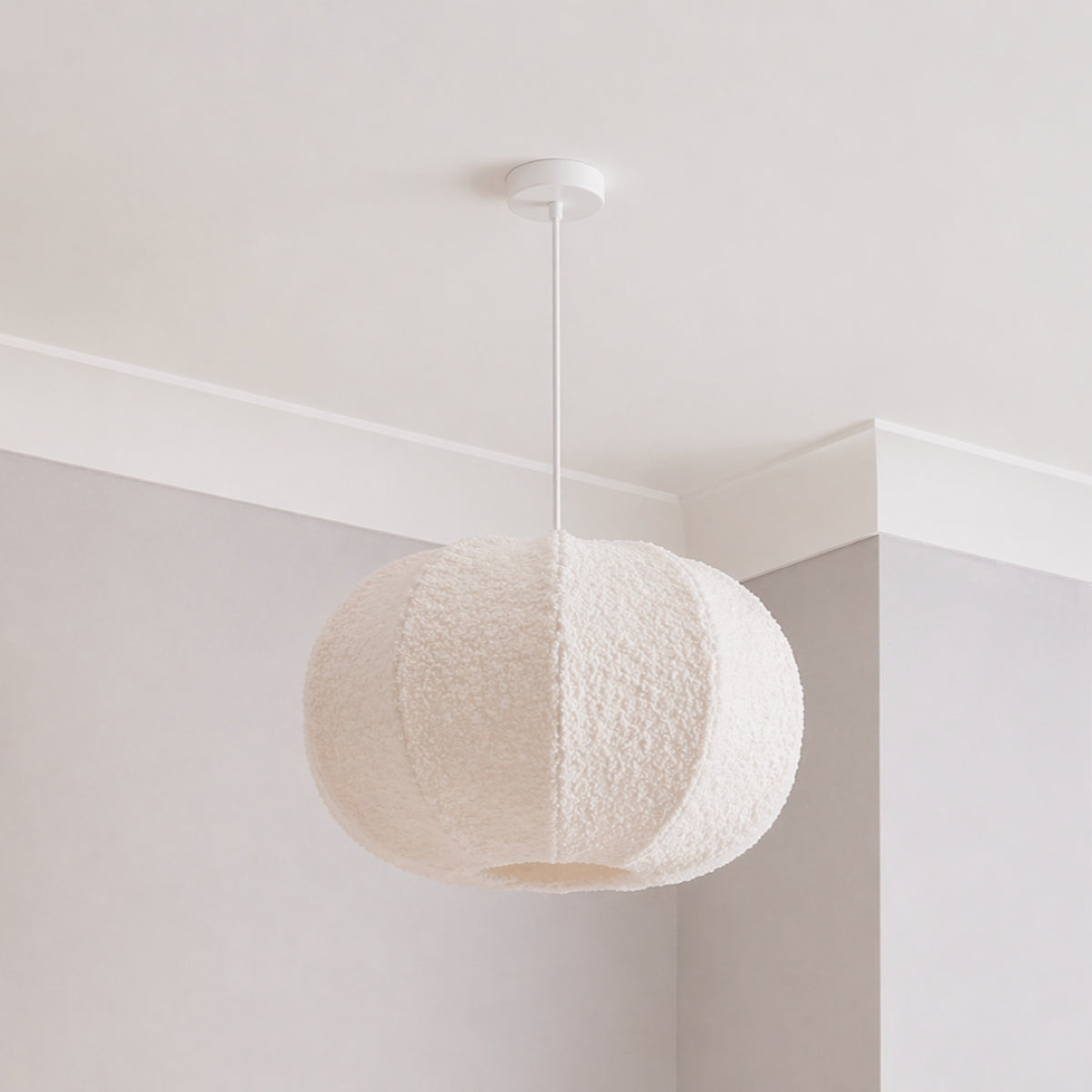 Textured pendant light hanging in a minimalistic room with white walls and ceiling.