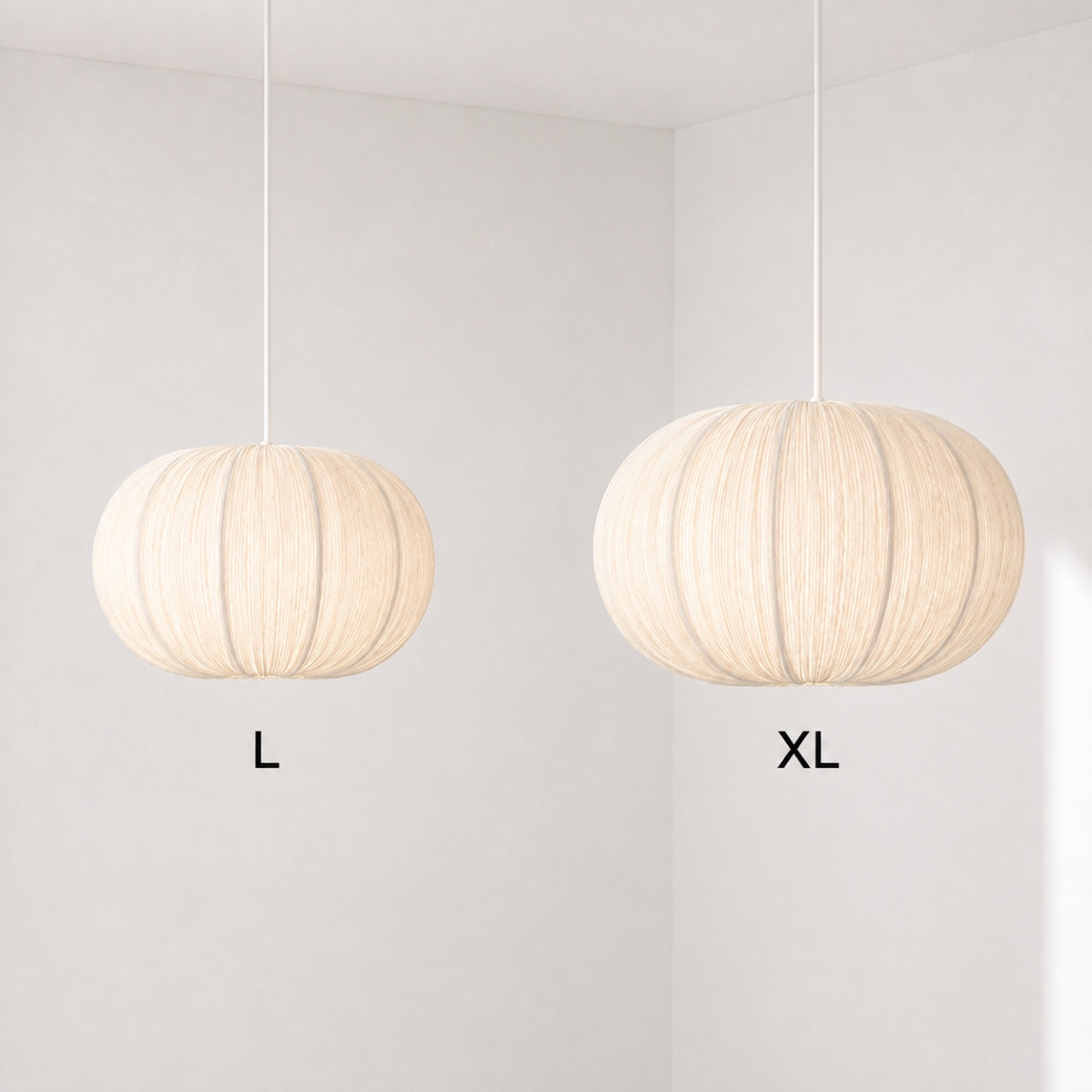 Two hanging pendant lights with ribbed cream fabric shades, labeled L and XL, shown in a minimalist white room corner.