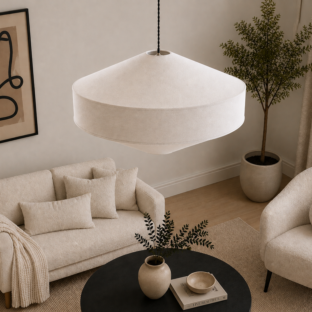 A modern living room scene featuring a large, dome-shaped off-white fabric pendant light hanging over a cream-colored sofa and matching armchair, with a black coffee table and abstract wall art in the background.