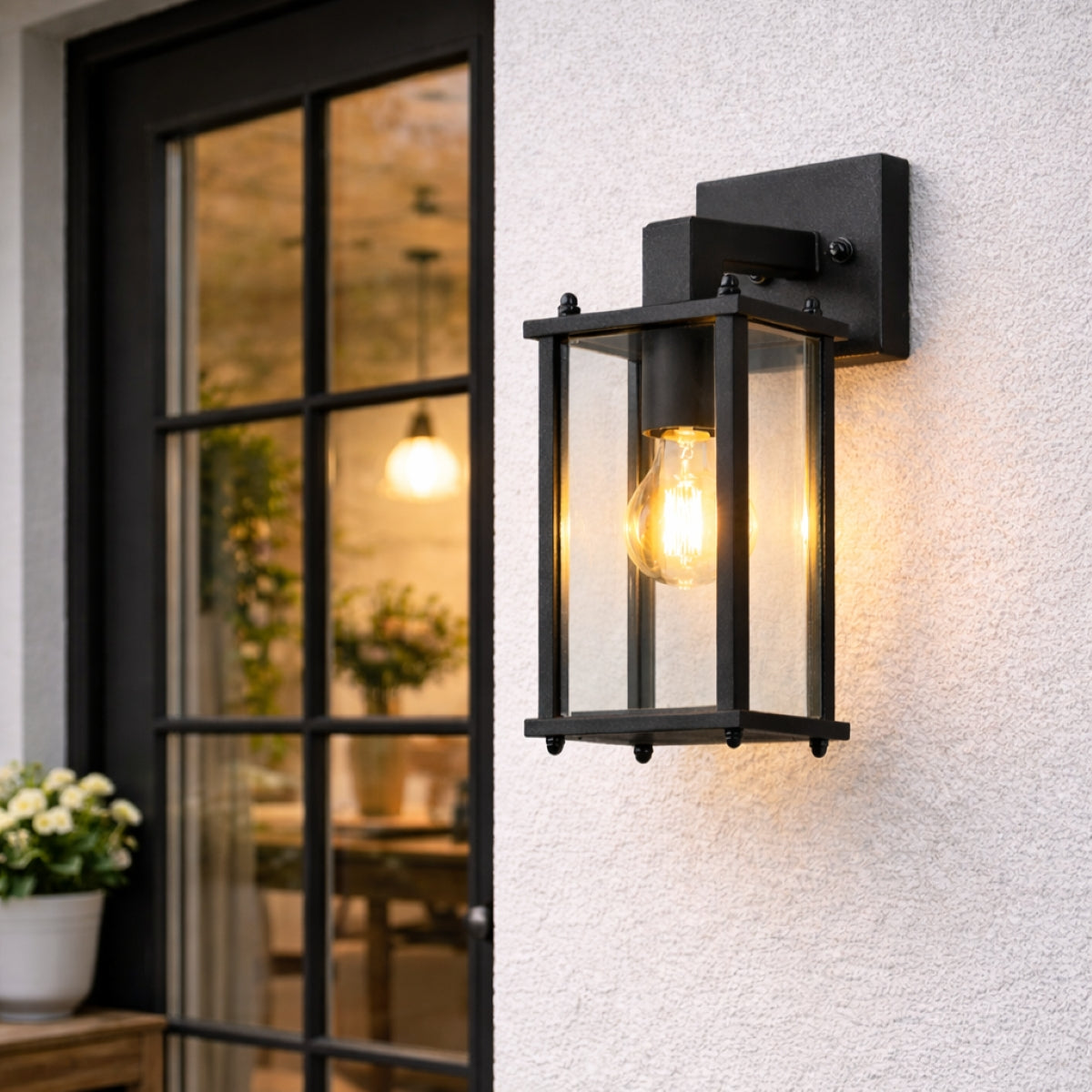 Black outdoor wall light fixture on a textured white wall with a blurred interior background.