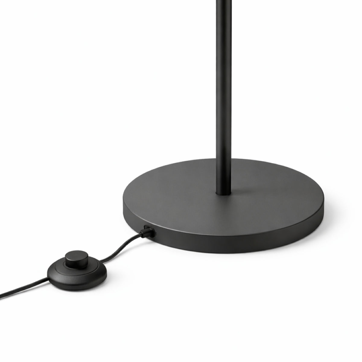 Black floor lamp with round base and cord on a white background