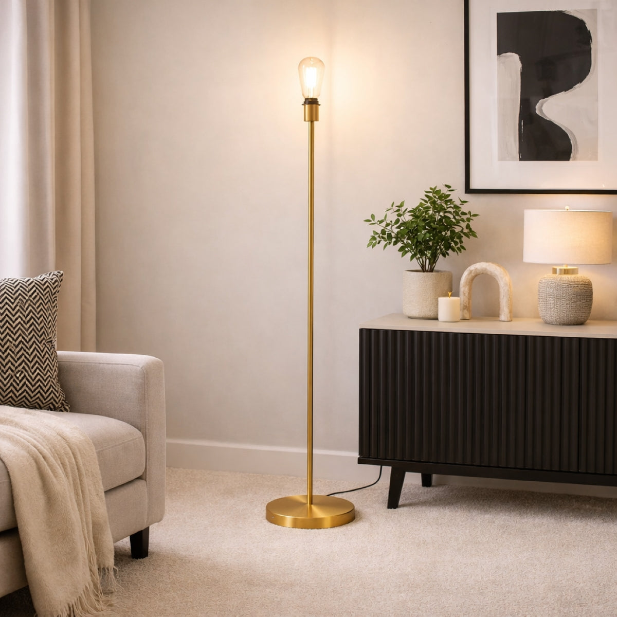 Gold floor lamp in a living room setting with a couch, plant, and side table.