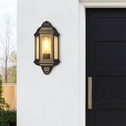 Decorative outdoor wall light fixture on a white wall next to a black door.
