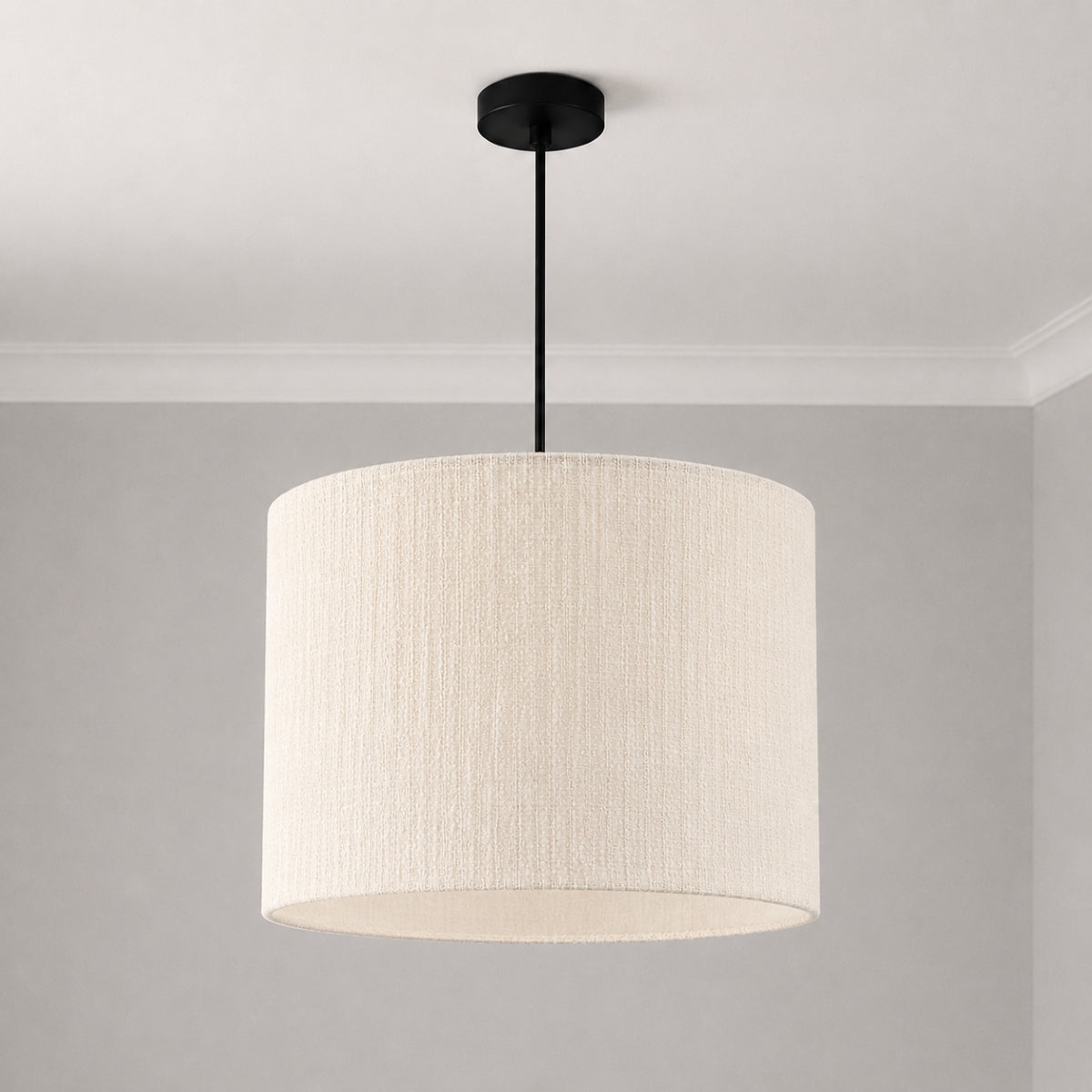 A modern drum pendant light with a textured off-white fabric shade and a matte black ceiling canopy and rod, shown hanging against a neutral gray wall and white ceiling.