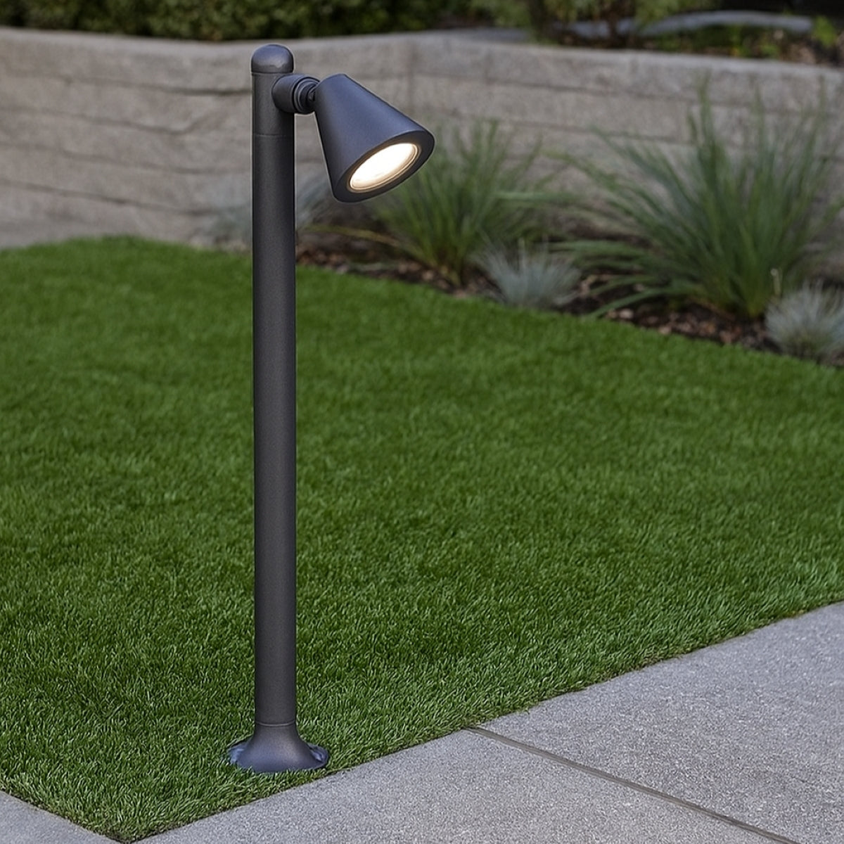 Outdoor garden light fixture on a grassy area with a stone wall in the background