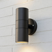 Black outdoor wall light fixture on a white brick wall