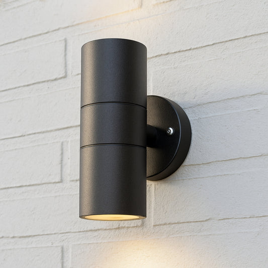 Black outdoor wall light fixture on a white brick wall