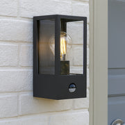 Black outdoor wall light fixture on a stone wall