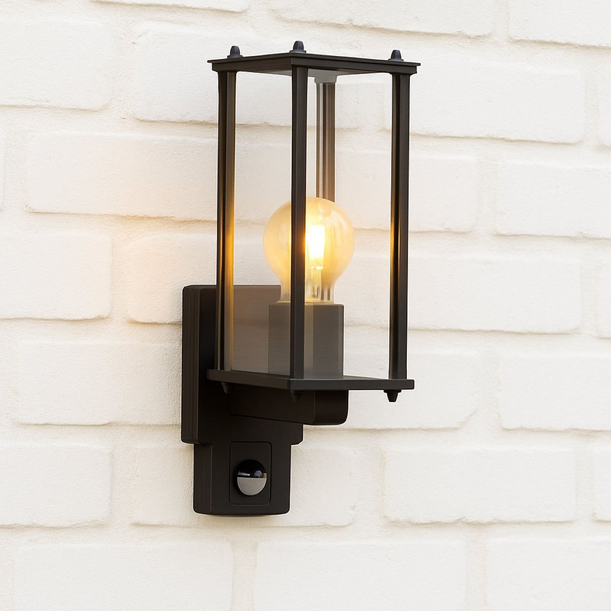 Black outdoor wall light fixture with glass cover on a white brick wall.