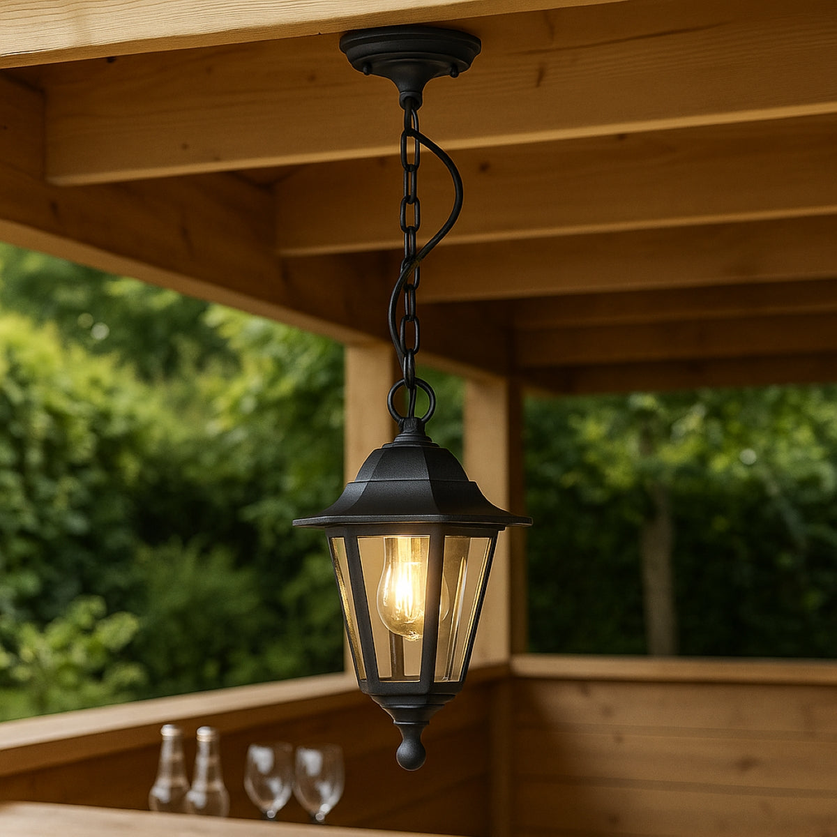 Black outdoor pendant light hanging from a wooden ceiling with greenery in the background