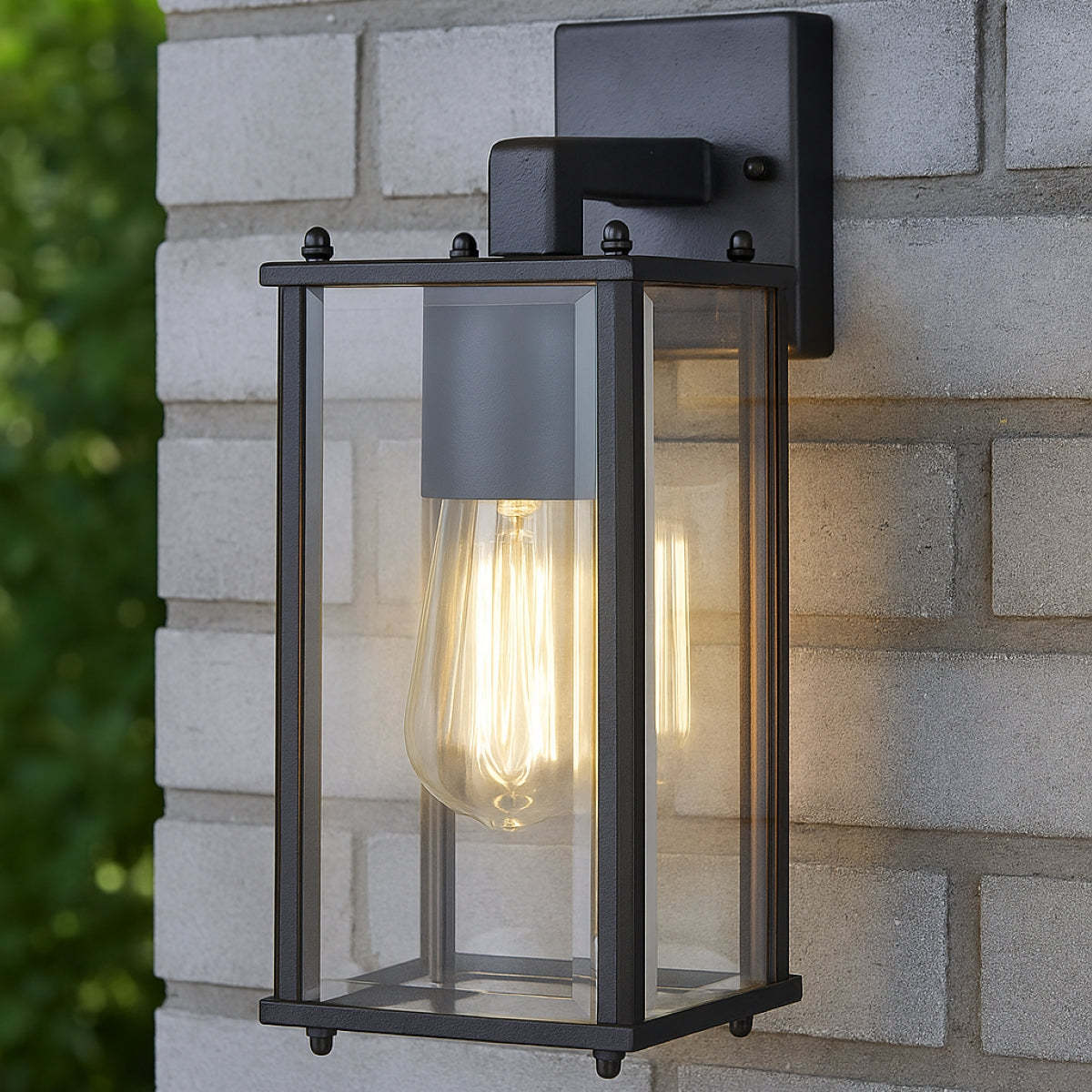 Black outdoor wall light fixture on a stone wall with blurred greenery.