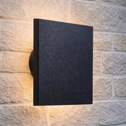 Black rectangular wall light fixture on a stone wall
