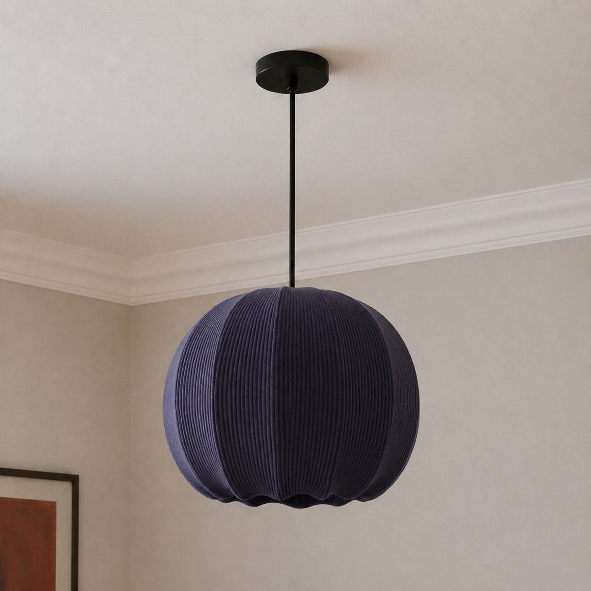 Spherical pendant light hanging from the ceiling in a room with neutral walls.