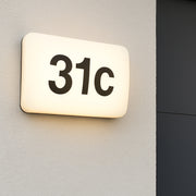 Lighted house number '31c' on a wall