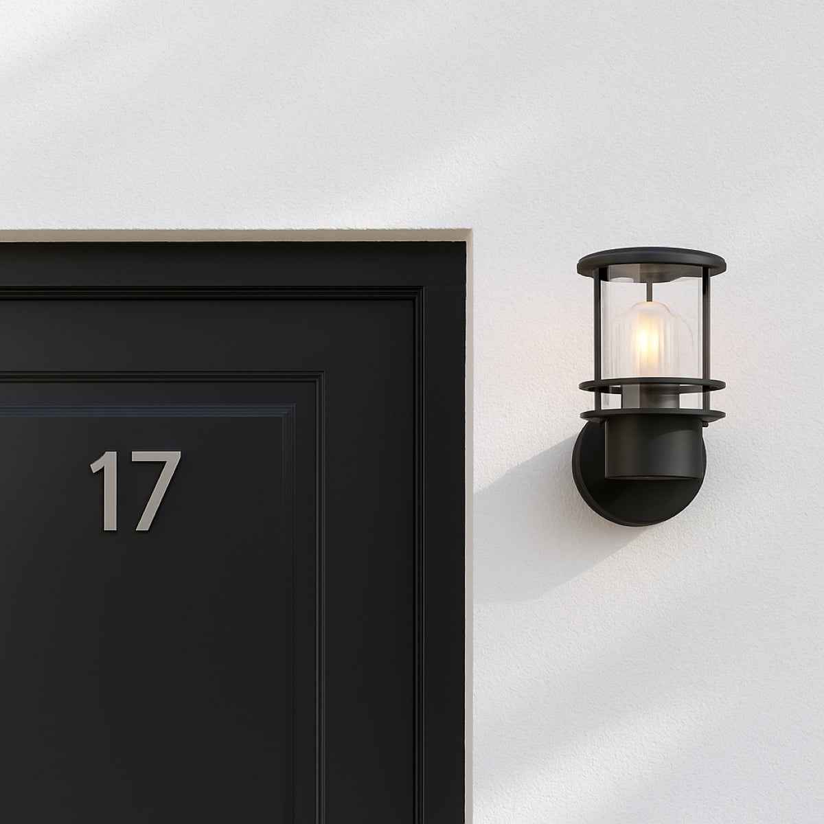 Black door with number 17 and wall-mounted light fixture on a white wall