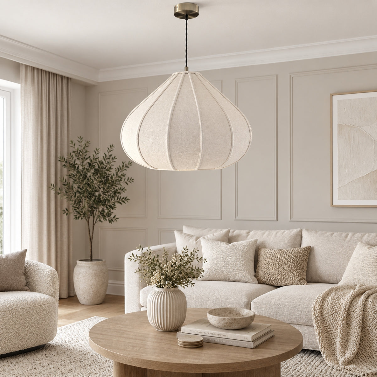 A modern teardrop-shaped pendant light with a textured cream fabric shade hangs in a bright, contemporary living room with a beige sofa, wooden coffee table, and neutral decor.