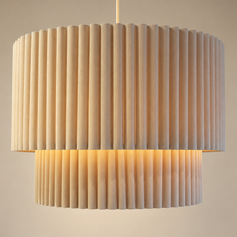 A modern two-tier drum pendant light with pleated fabric shades, shown illuminated against a warm neutral background.