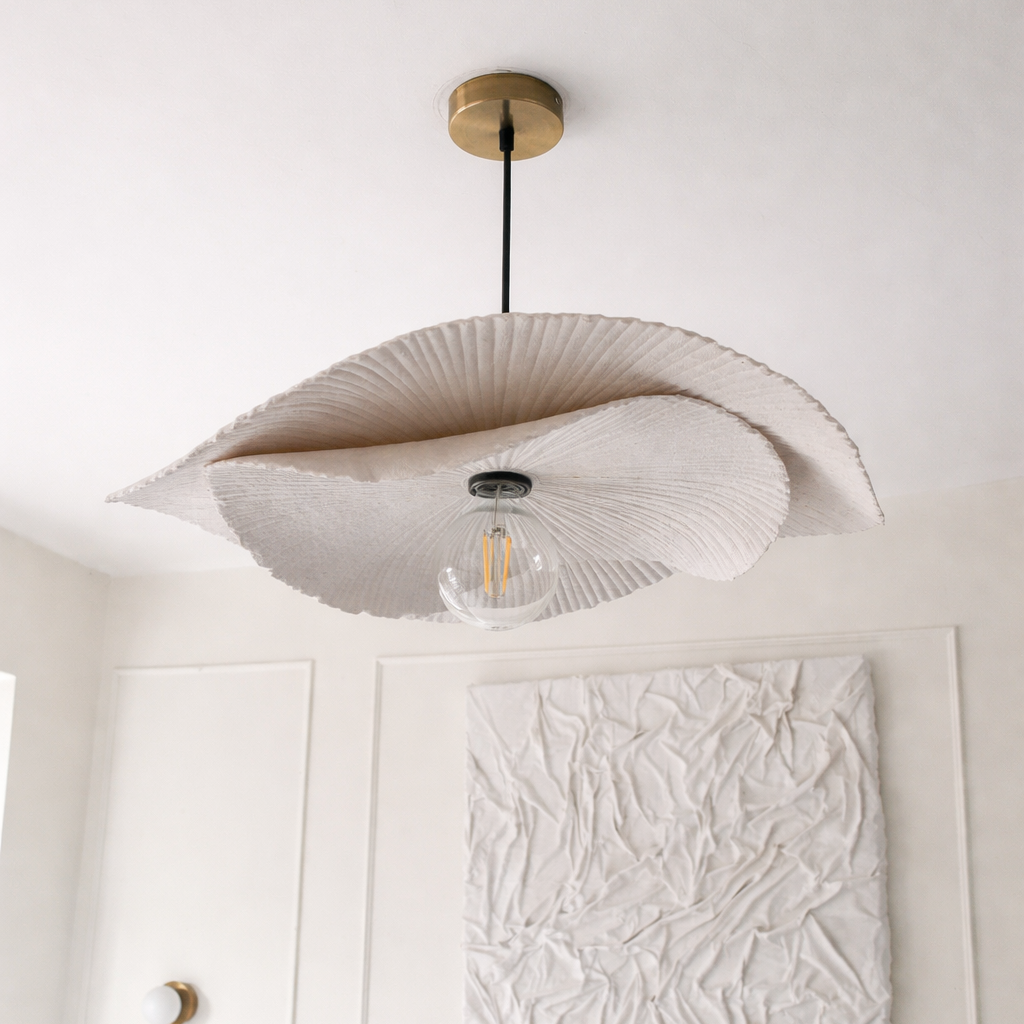 Ceiling light fixture with decorative shade in a room with white walls and furniture.