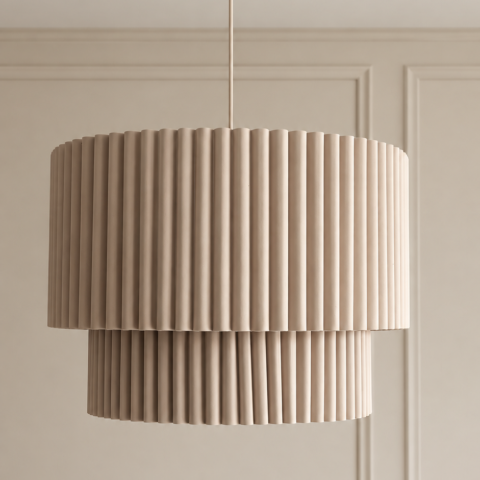A modern two-tiered drum pendant light with a pleated fluted design in a warm beige tone, hanging against a matching beige paneled wall.