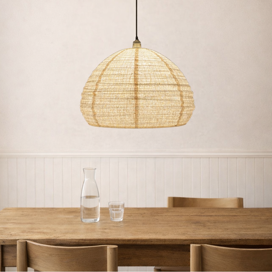 Woven pendant light hanging above a wooden dining table with a neutral wall background.