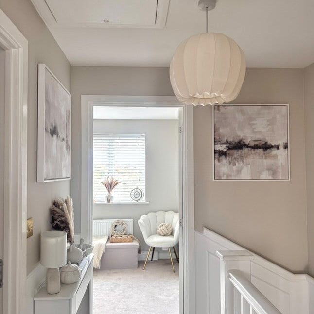 Nursery with white crib, round pendant light, and abstract wall art.