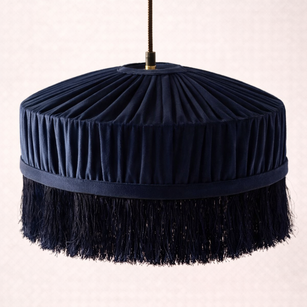 Navy blue pleated lampshade with tassels on a plain background