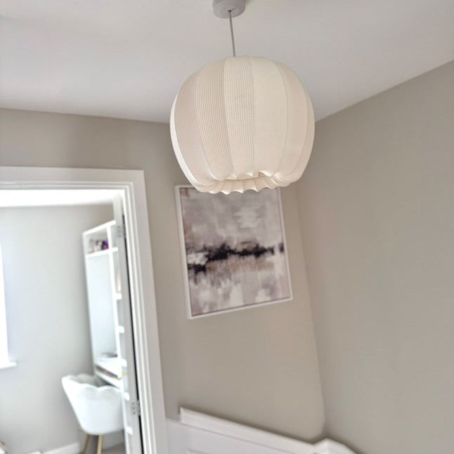 Ceiling light fixture in a room with neutral walls and a piece of abstract art.