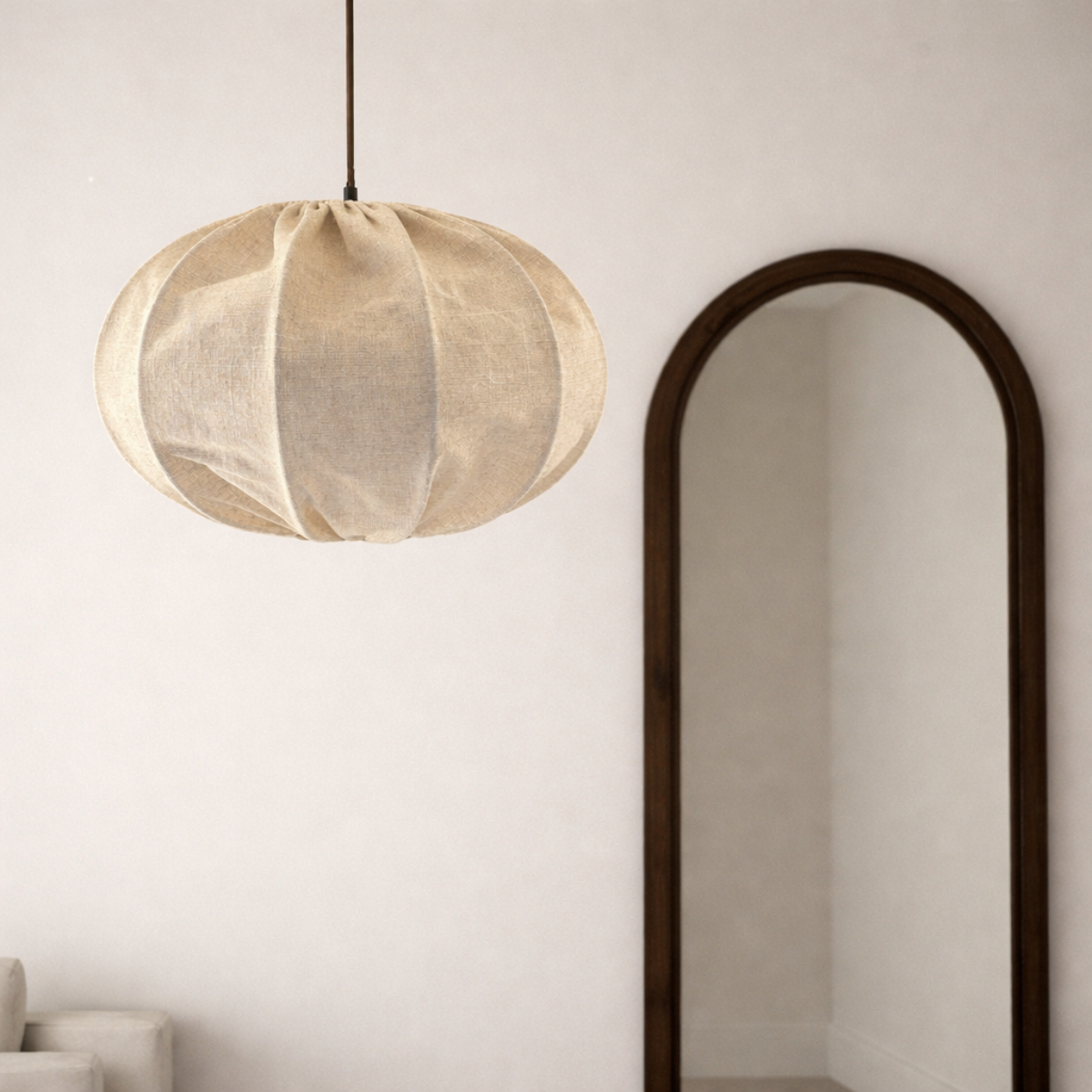 Beige pendant lamp hanging above a sofa with a mirror on the wall.