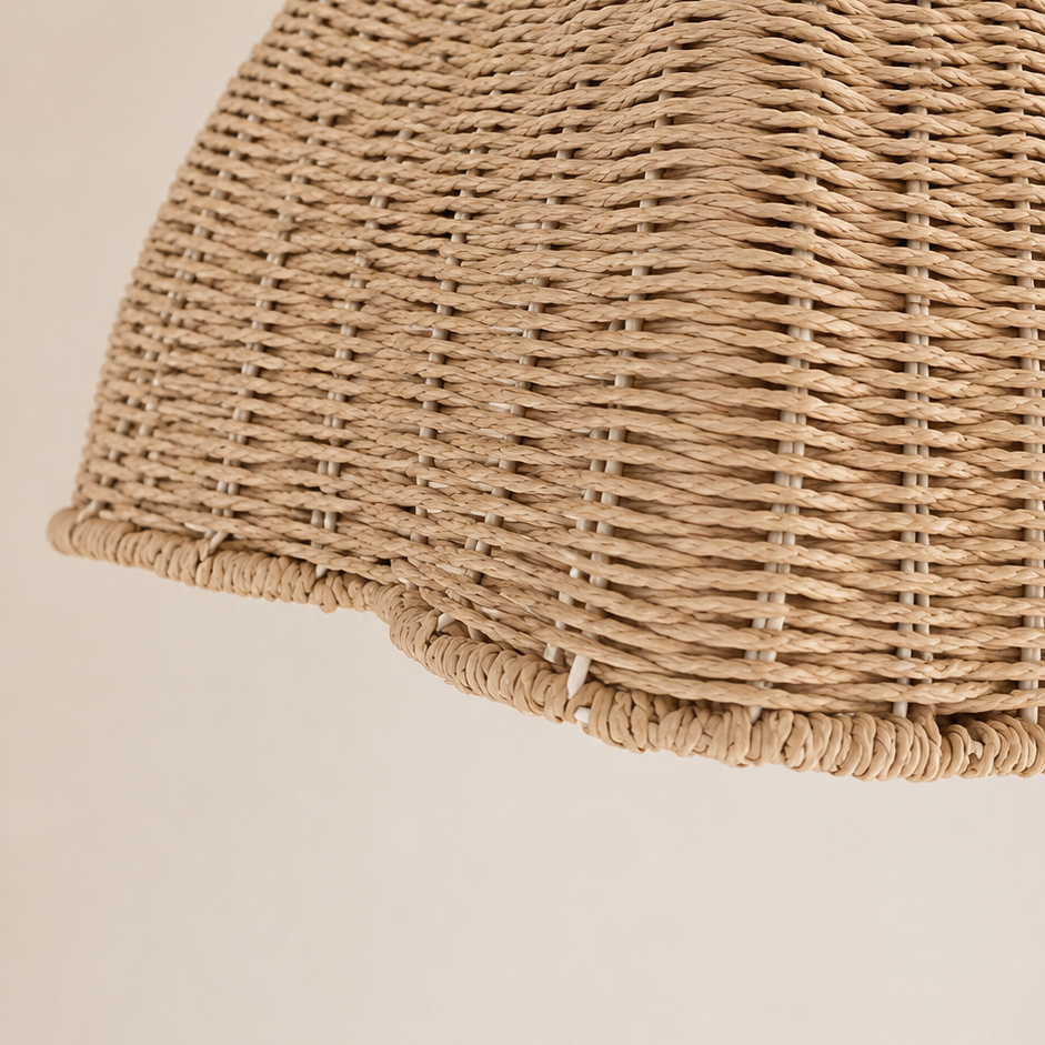 Close-up of a woven natural fiber dome pendant light shade hanging against a plain warm beige background.