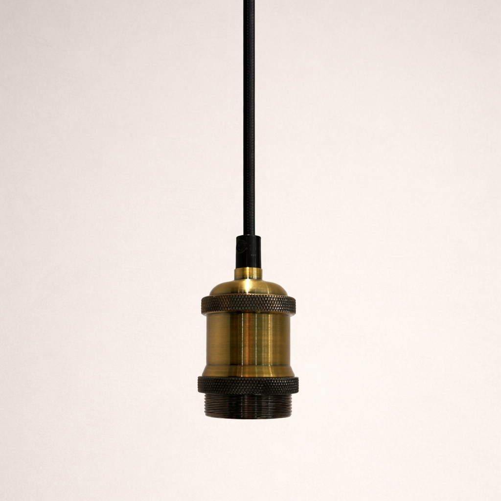 Brass pendant light with black cord on a white background
