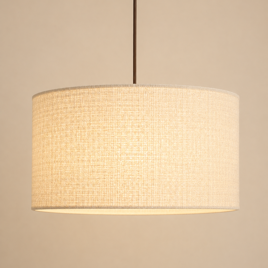 A drum pendant light with a textured beige linen shade, suspended by a thin dark brown rod against a solid beige background.