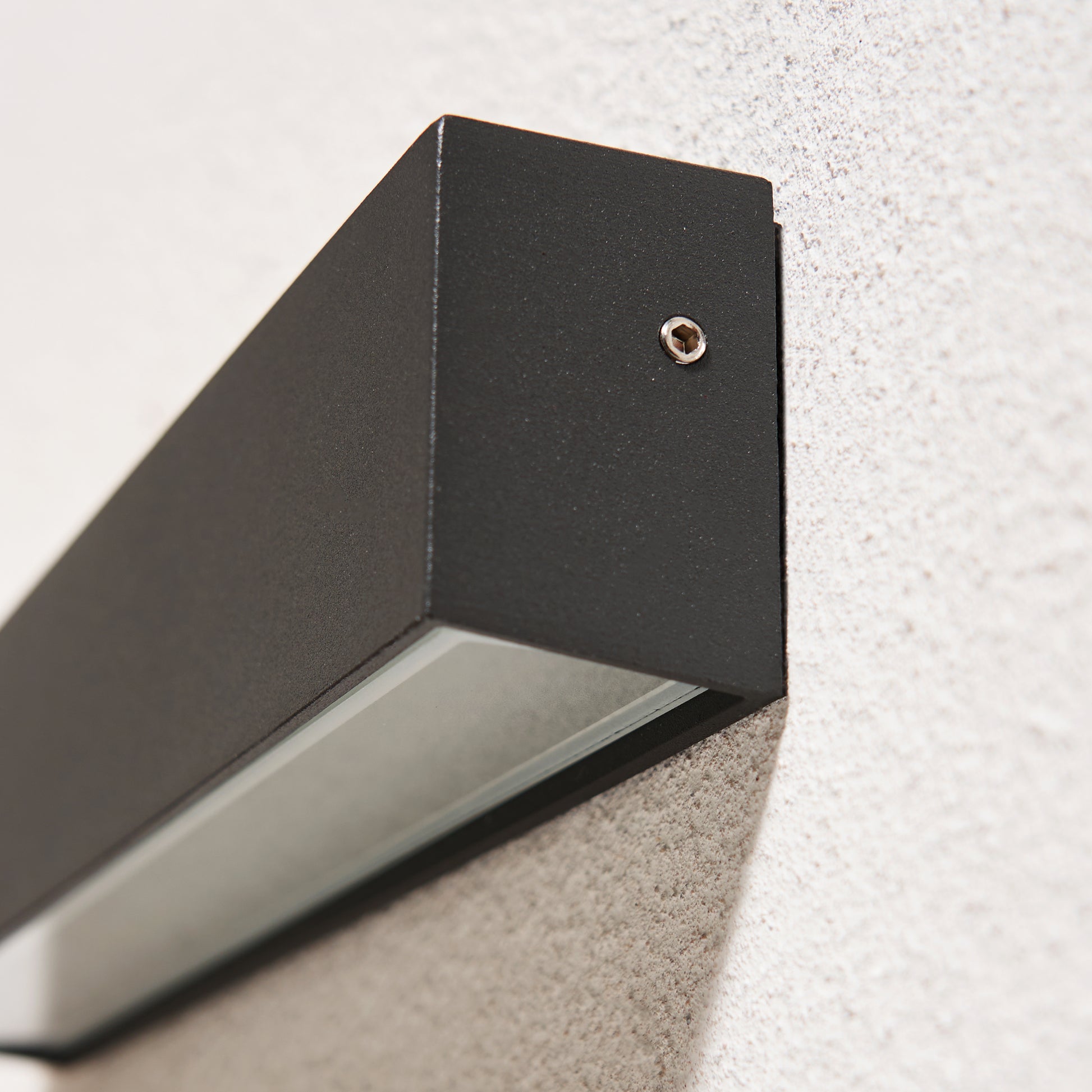 Black outdoor wall light fixture mounted on a textured wall.