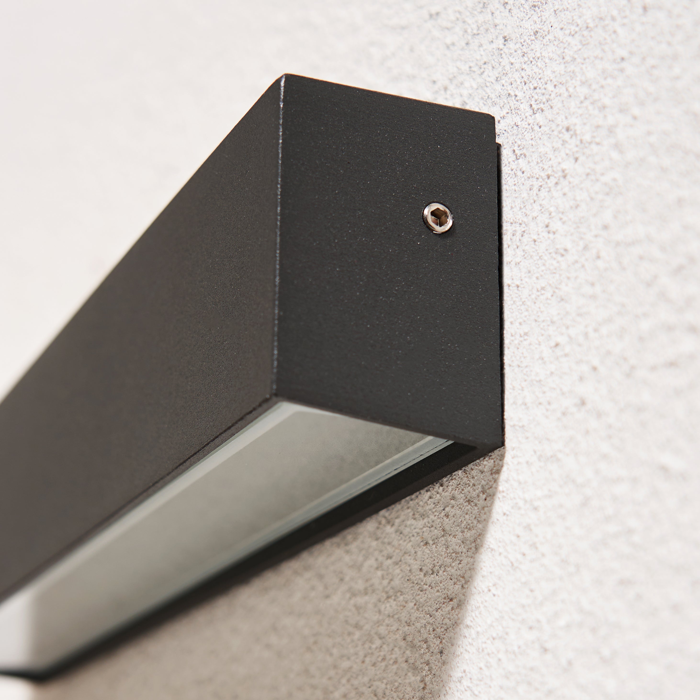 Black outdoor wall light fixture mounted on a textured wall.