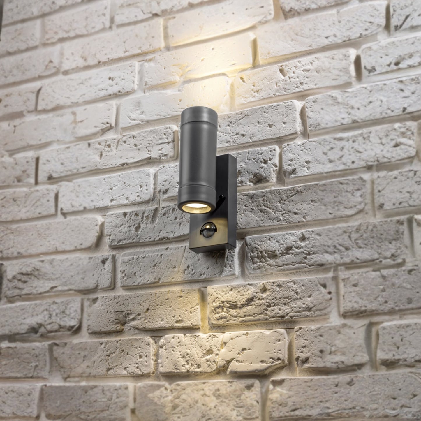 Our Valentine dark grey outdoor wall mounted up and down cylinder outdoor light with motion sensor would look perfect in a modern or more traditional home design. Outside wall lights can provide atmospheric light in your garden, at the front door or on the terrace as well as a great security solution. It is designed for durability and longevity with its robust material producing a fully weatherproof and water resistant light fitting.