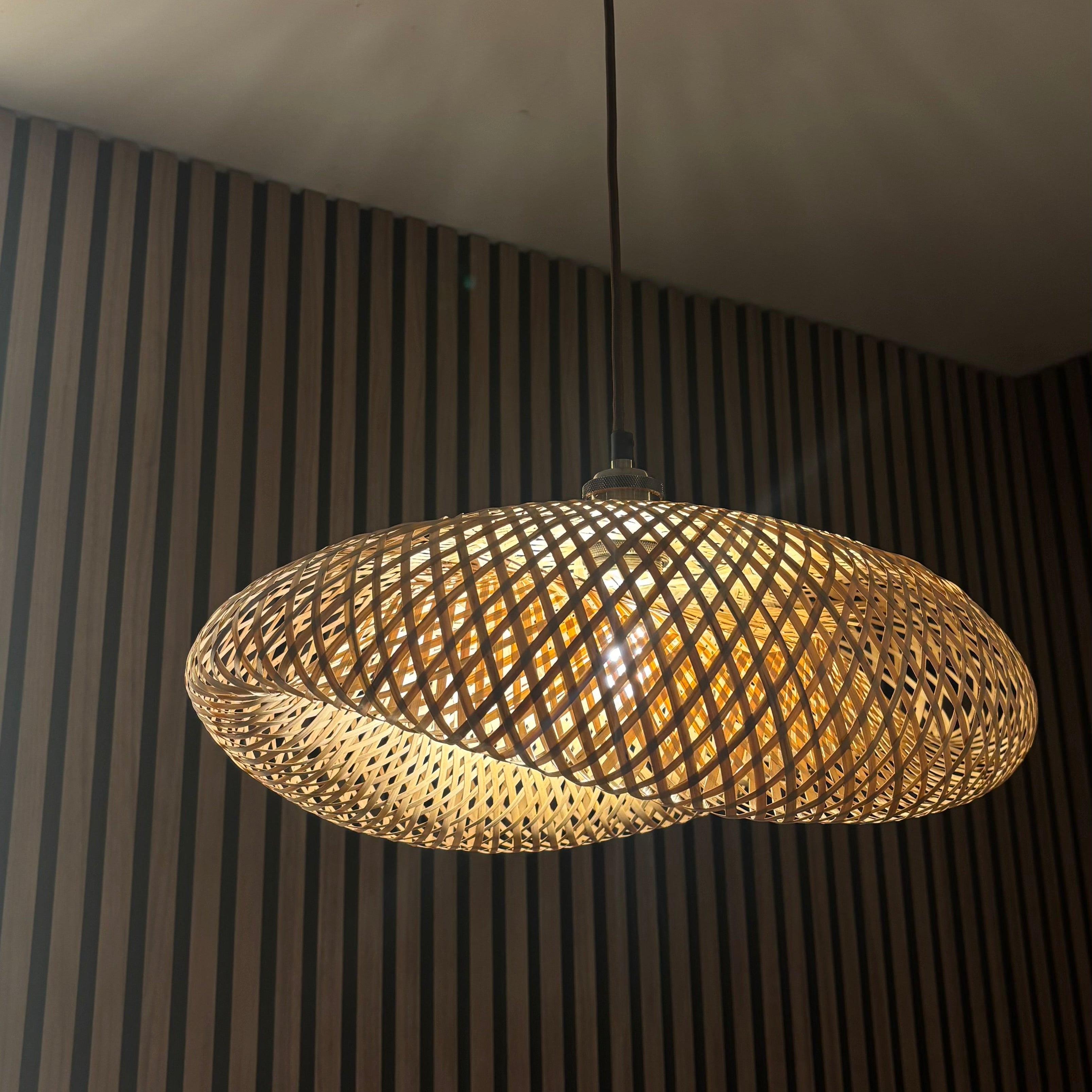 Decorative pendant light hanging from a ceiling with a striped wall in the background