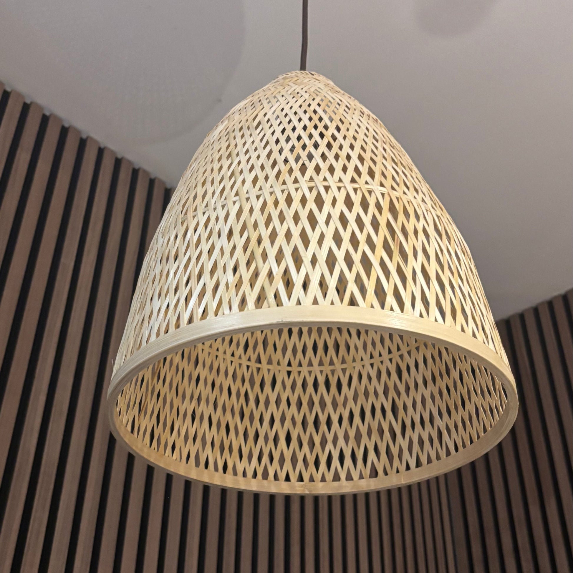 Woven rattan pendant light hanging against a striped wall.