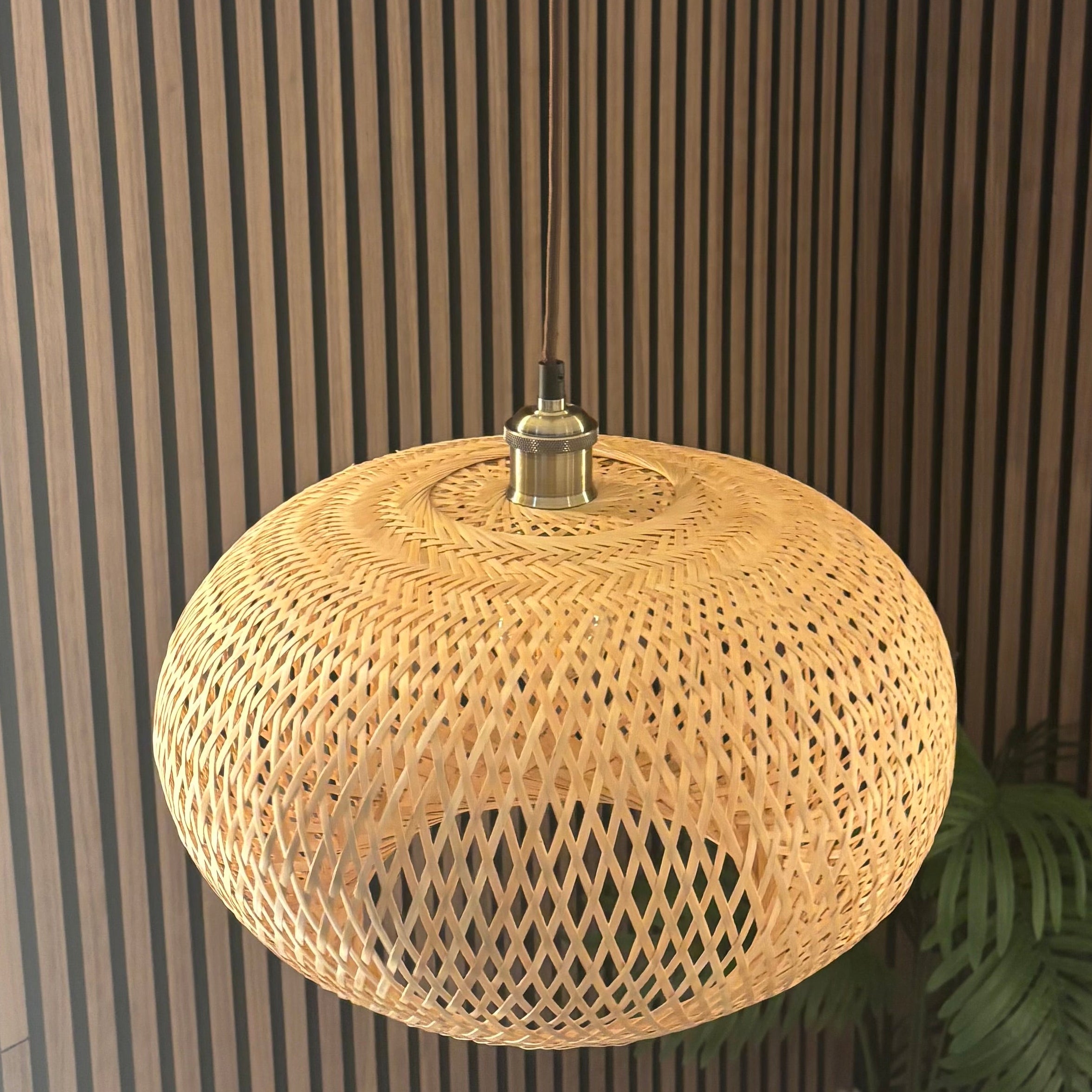 Woven pendant light hanging from the ceiling with striped wall in the background