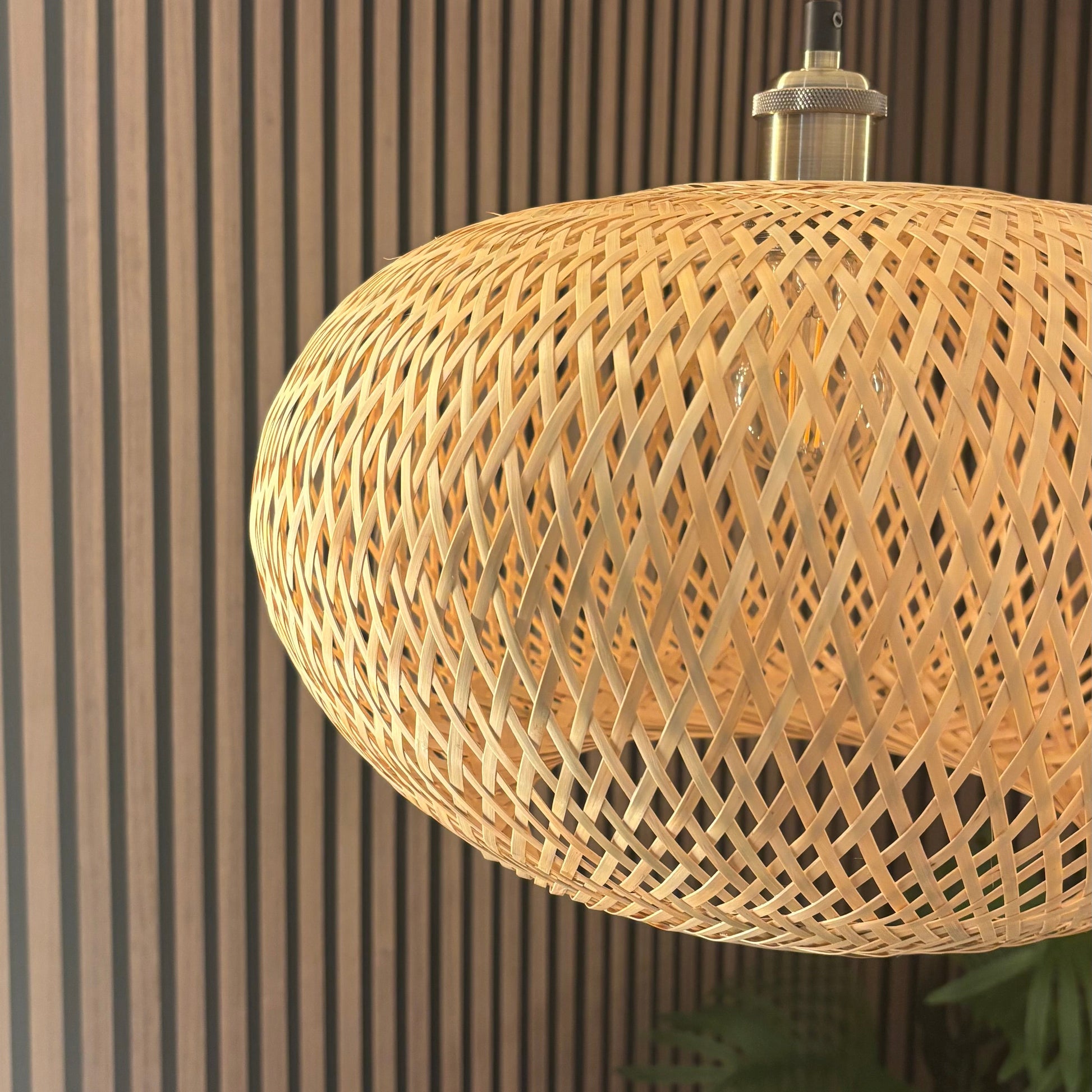Woven rattan pendant light against a striped wall.
