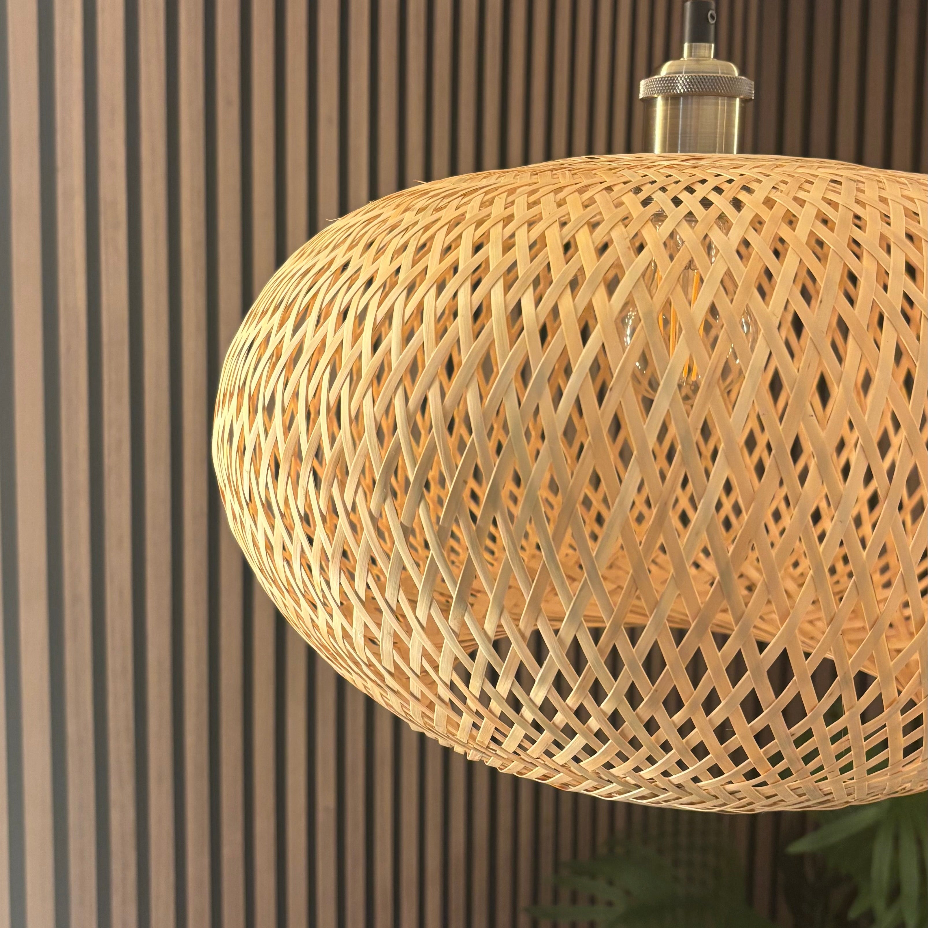 Woven rattan pendant light against a striped wall.